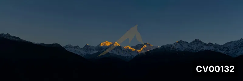 Ảnh panorama dãy núi tuyết hùng vĩ dưới ánh bình minh vàng rực trên nền trời xanh thẫm.