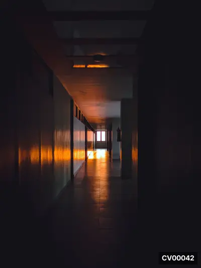 Hành lang dài trong nhà, trần gỗ, ánh sáng vàng hắt lên tường và sàn gạch vào ban đêm.