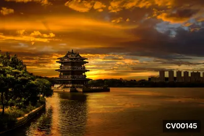 Mặt hồ phản chiếu ánh cam hoàng hôn, bên cạnh là lầu cổ ba tầng mái uốn cong và dải cây rậm phía trái.