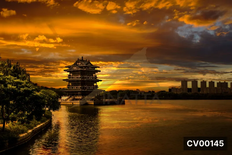 Mặt hồ phản chiếu ánh cam hoàng hôn, bên cạnh là lầu cổ ba tầng mái uốn cong và dải cây rậm phía trái.