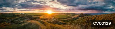 Ảnh chụp toàn cảnh hoàng hôn trên những đồi cỏ xanh ven biển dưới bầu trời mây kịch tính.