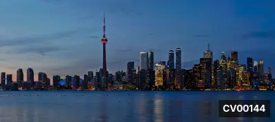 Bờ hồ phía trước thành phố Toronto, tháp CN cao vút giữa các tòa nhà sáng đèn, hồ nước phẳng phản chiếu ánh đèn.
